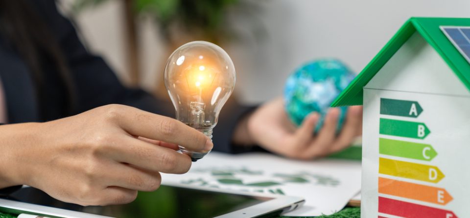 Energielabel huisje met iemand die een lamp en wereldbol vasthoudt