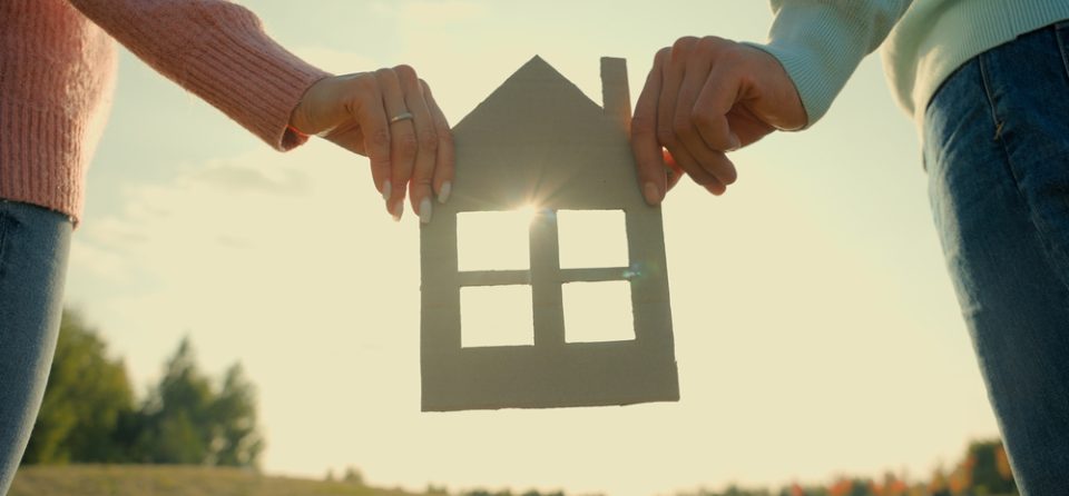 twee mensen houden hout huisje vast
