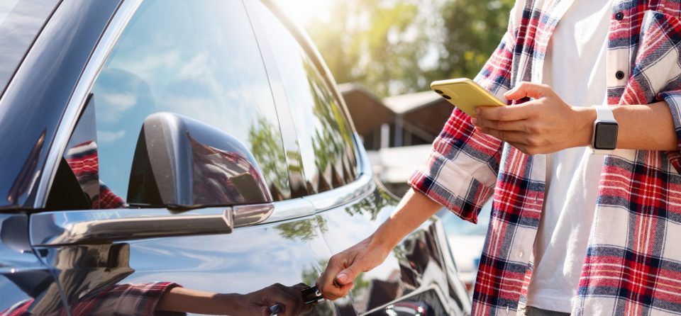 Man bij auto met mobiel